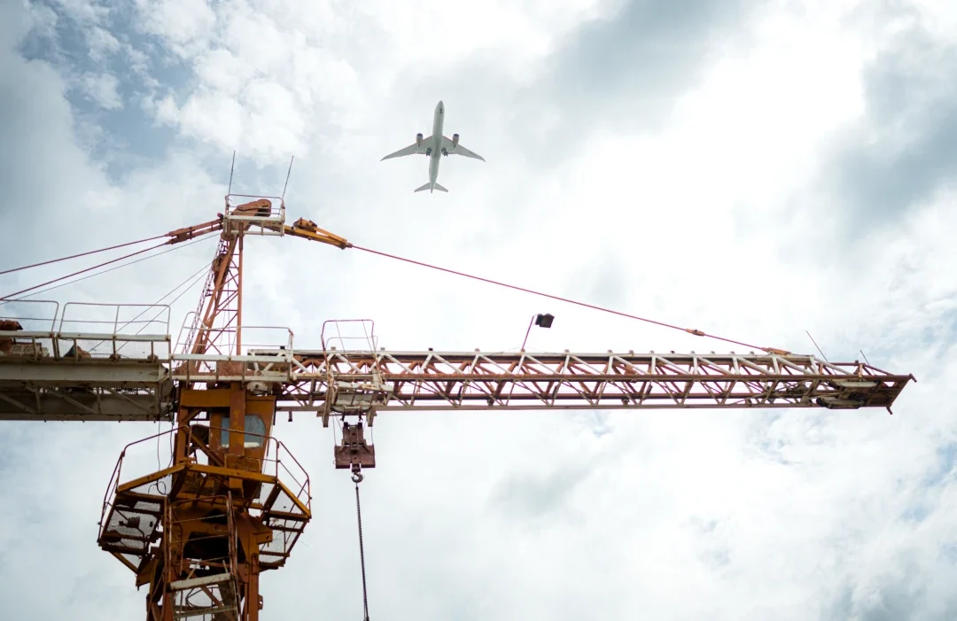 tower-crane-in-at-construction-site-with-air-plane-2024-07-26-13-44-16-utc